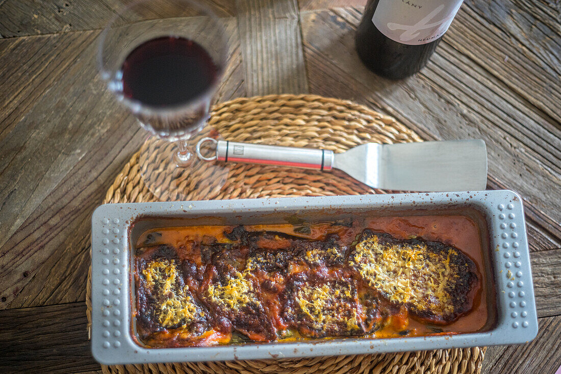 A dish of eggplant parmesan, freshly baked and ready to be served, on a wooden table in Seville, Spain.