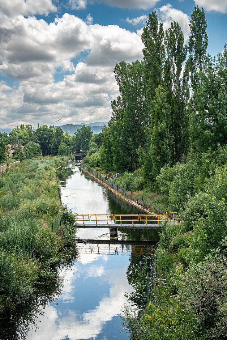 Nature scene of an irrigation canal in Puente del Congosto, a town in the province of Salamanca, Spain, surrounded by trees and greenery.