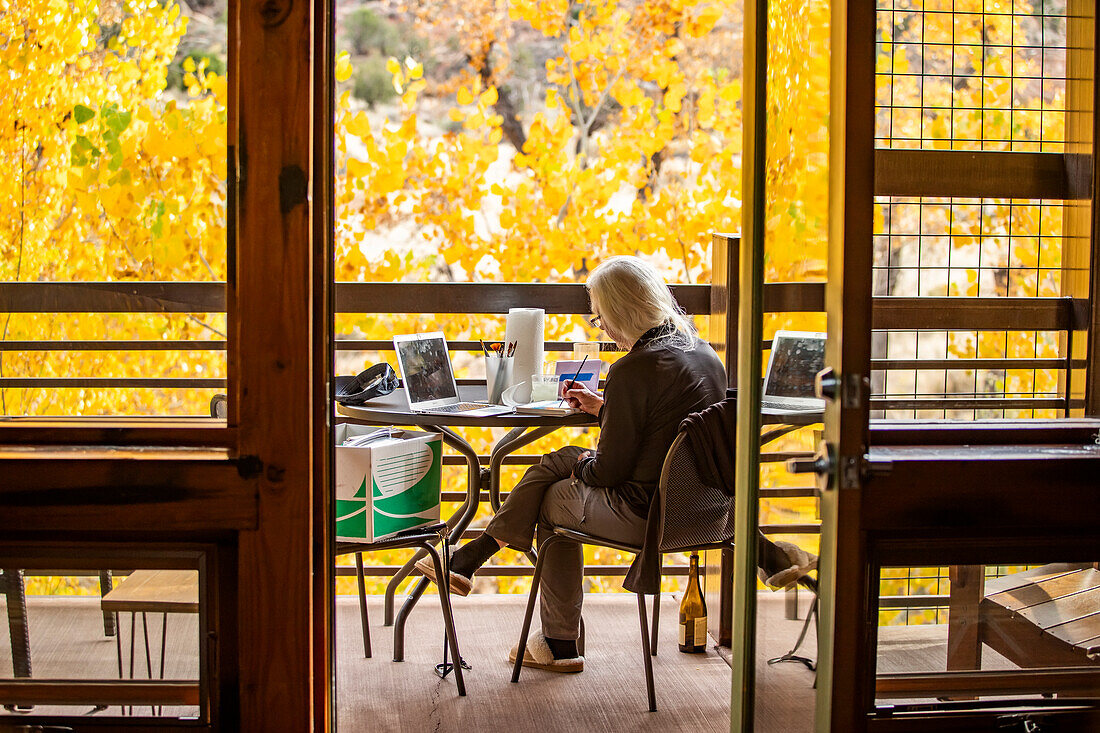 Woman painting with watercolors on porch in autumn