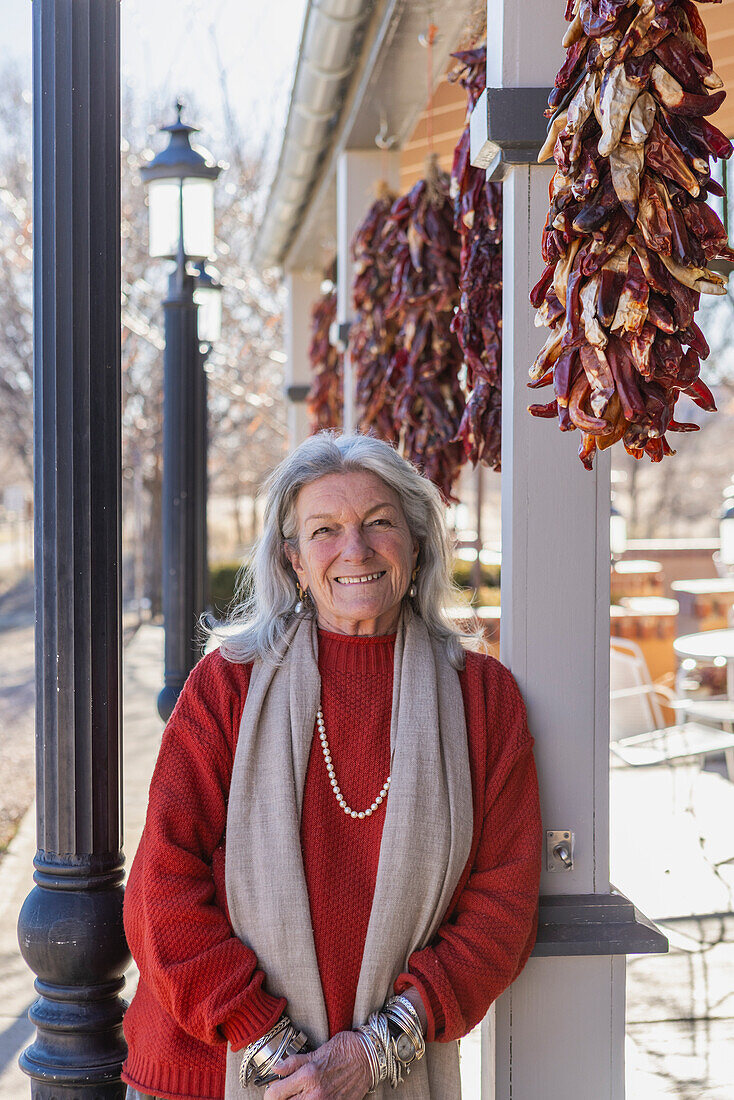 Portrait of smiling woman leaning against column at sidewalk cafe