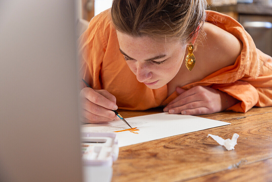 Teenage girl painting with watercolors at table