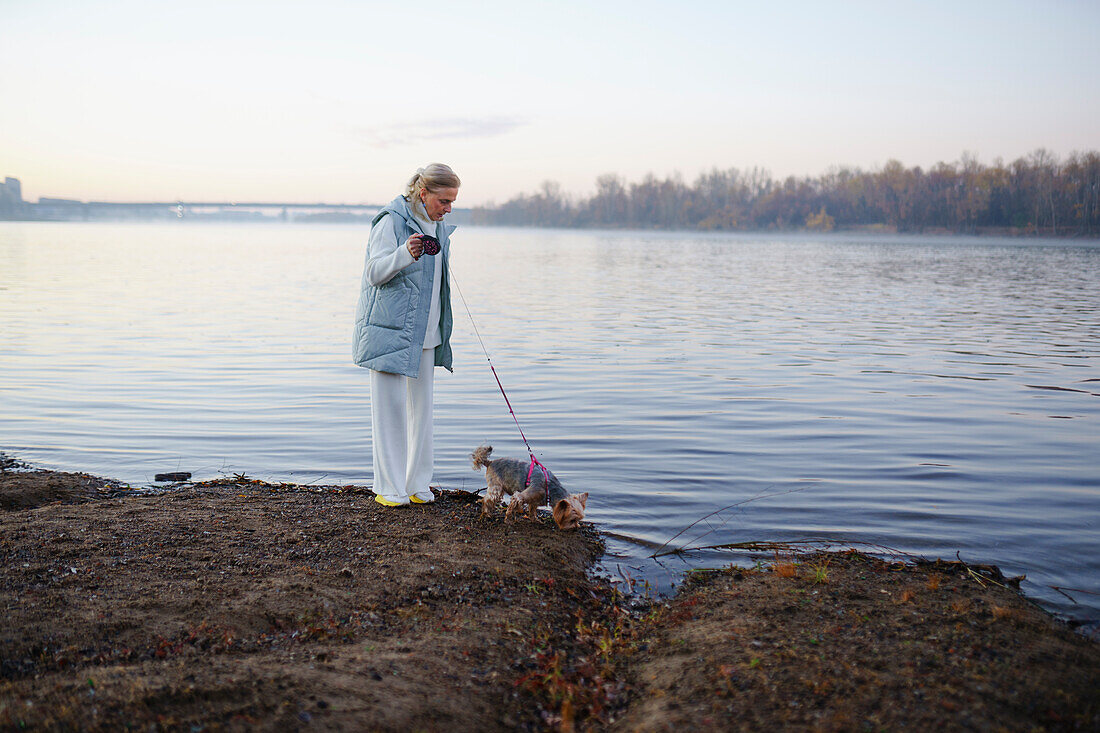 Woman with Yorkshire Terrier on lakeshore