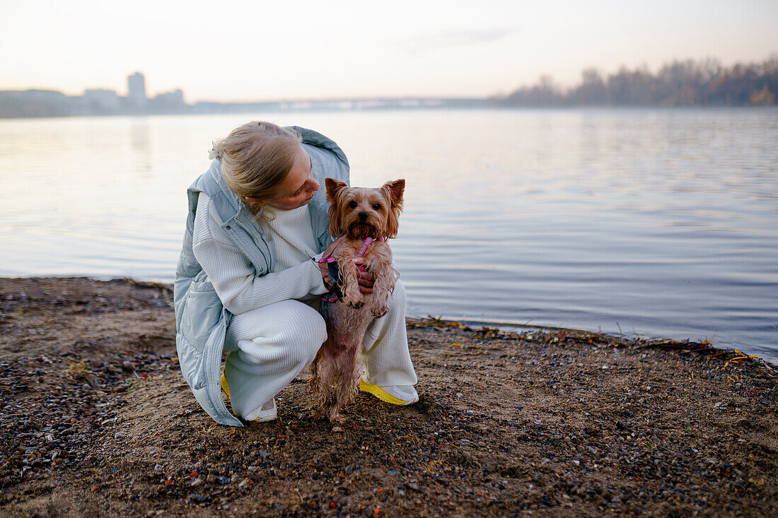 Frau mit Yorkshire Terrier am Seeufer