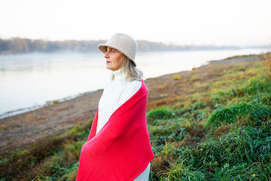 Portrait of woman wrapped in red shawl on lakeshore