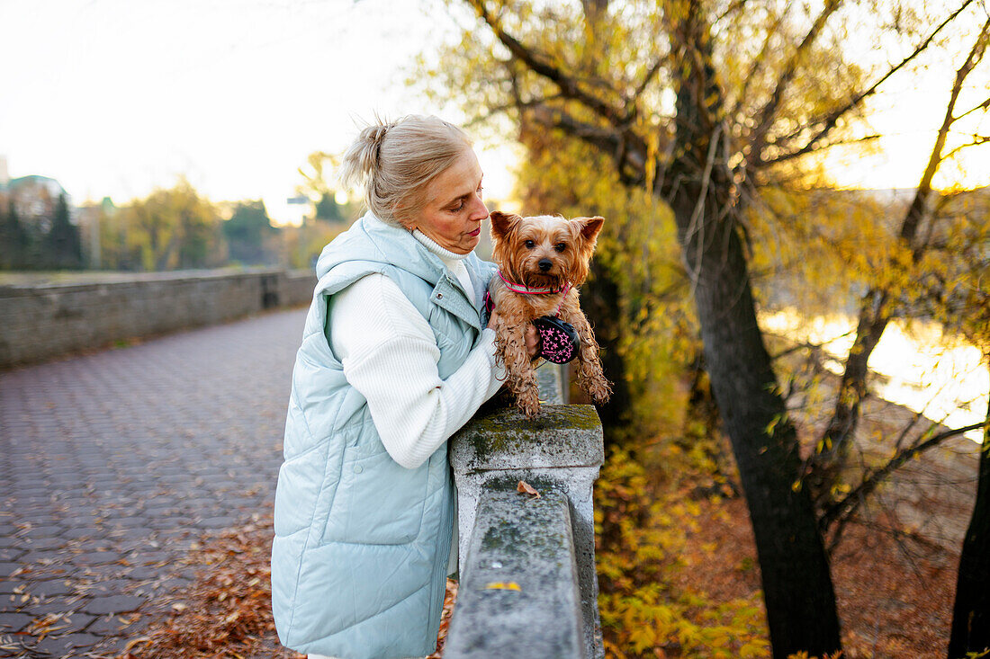 Woman with Yorkshire Terrier by river in autumn