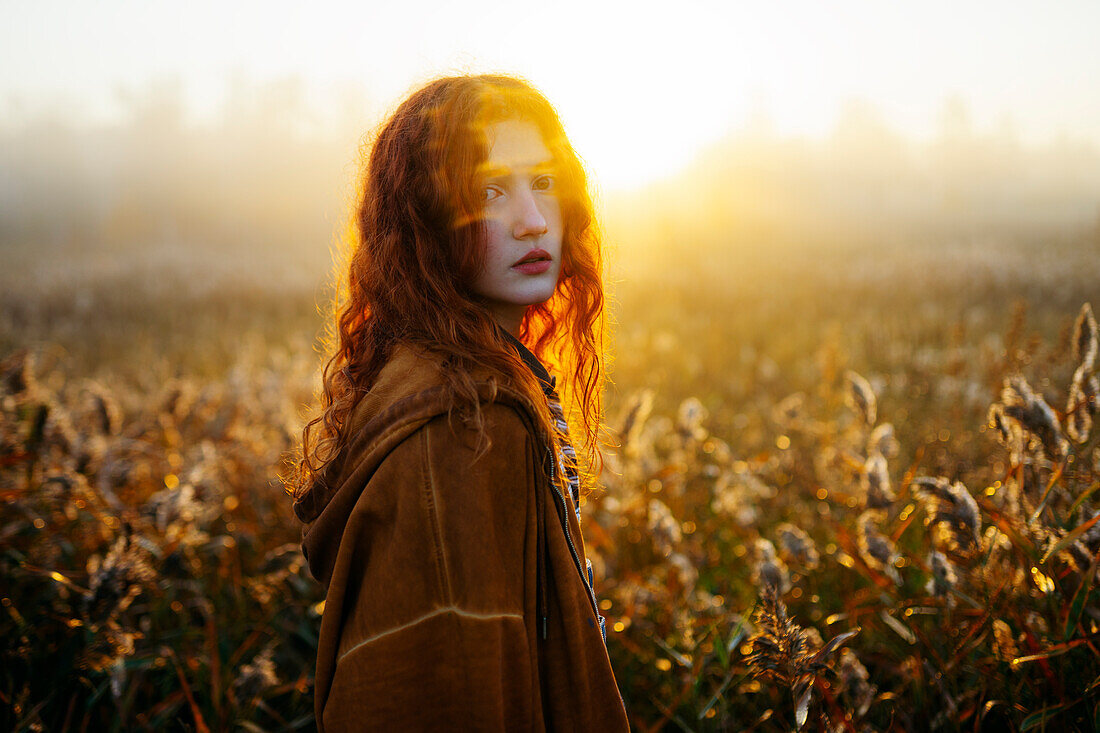 Portrait of redhead women in foggy field in autumn