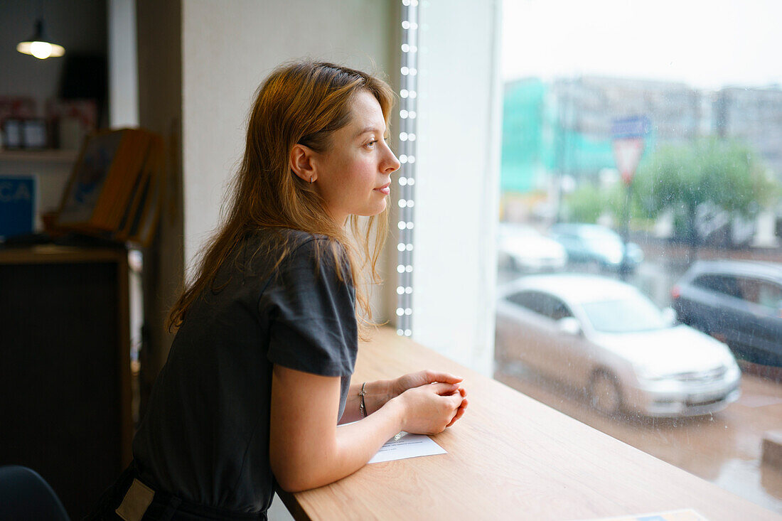 Woman leaning on window sill and looking through window