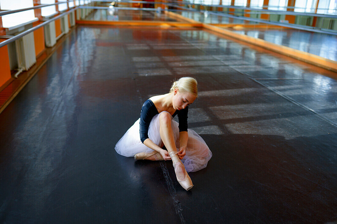 Ballerina sitting on floor in ballet studio