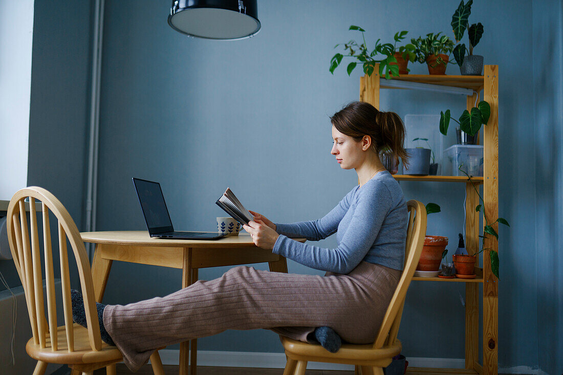 Frau liest zu Hause am Tisch