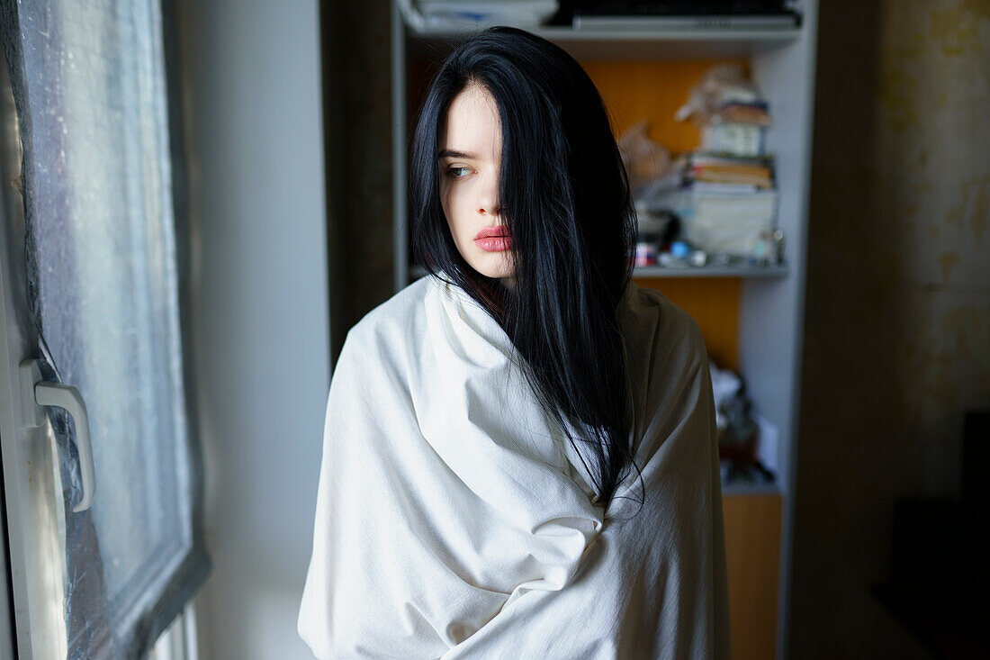 Portrait of pensive woman wrapped in white sheet