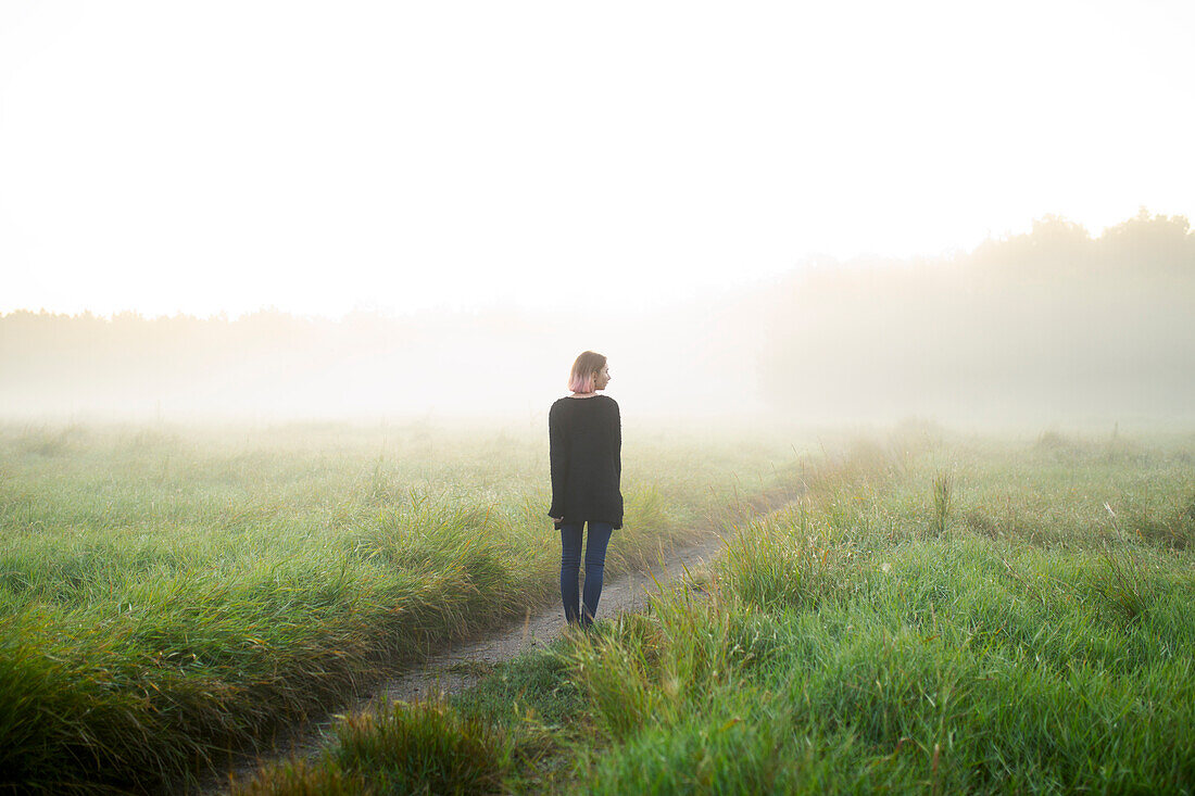 Rear view of woman standing in foggy field