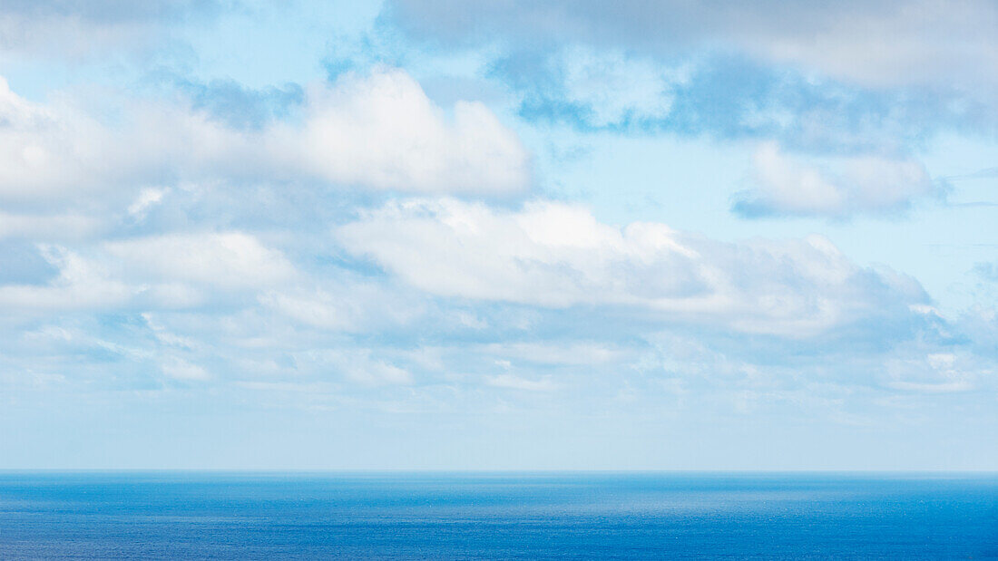 White puffy clouds above calm sea