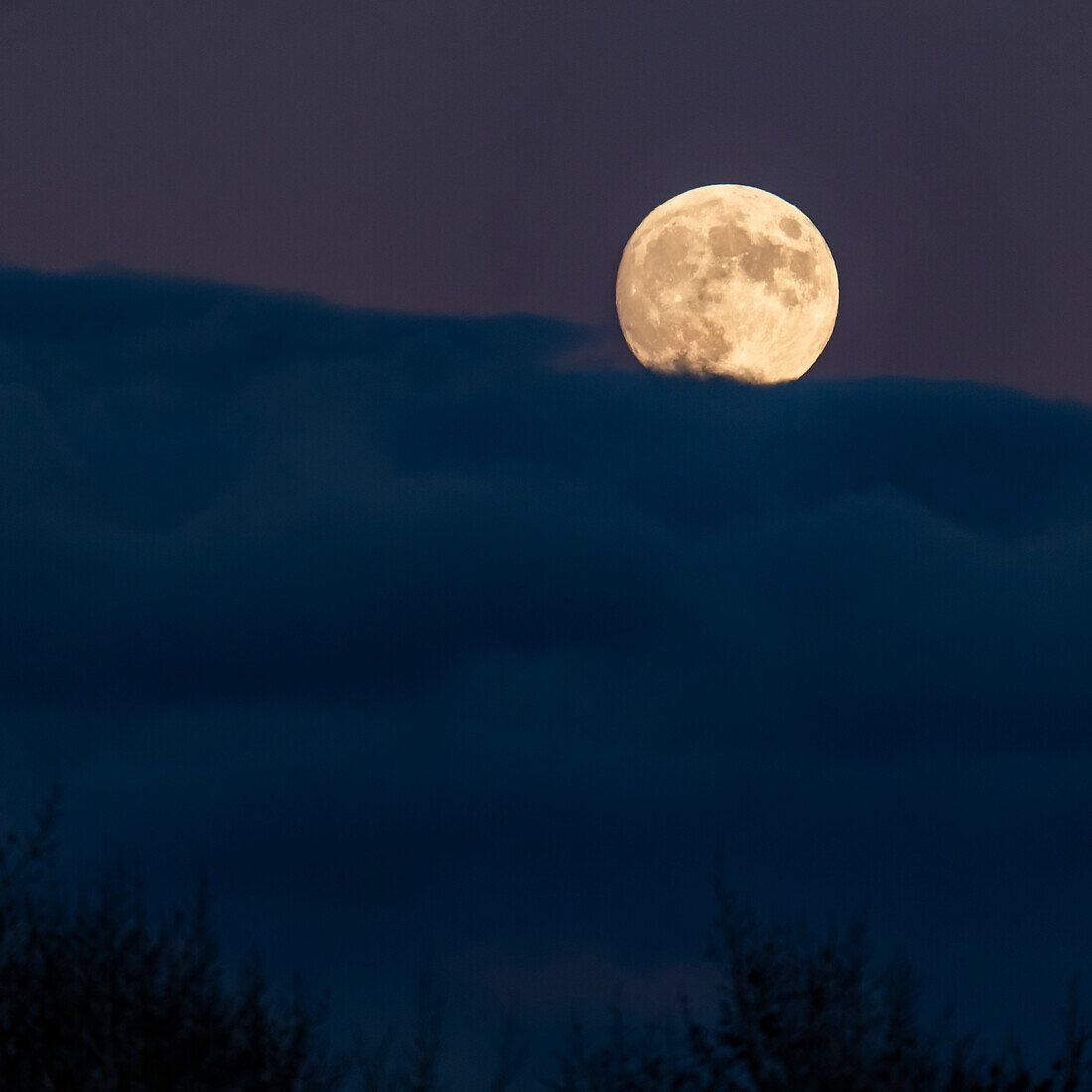 Full moon rising over clouds