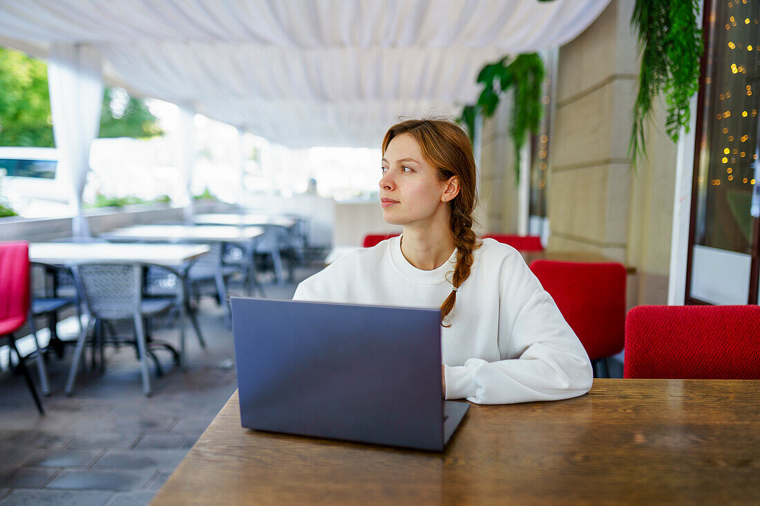 Nachdenkliche Frau mit Laptop am Cafétisch