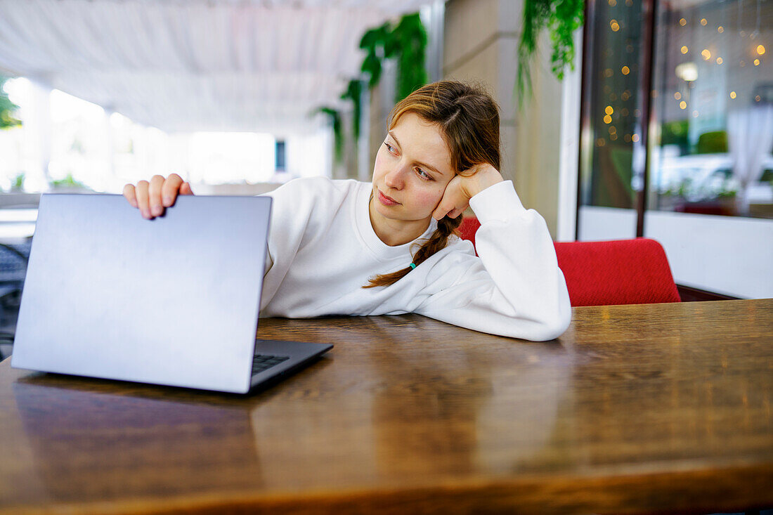 Frau mit Blick auf den Laptop am Cafétisch