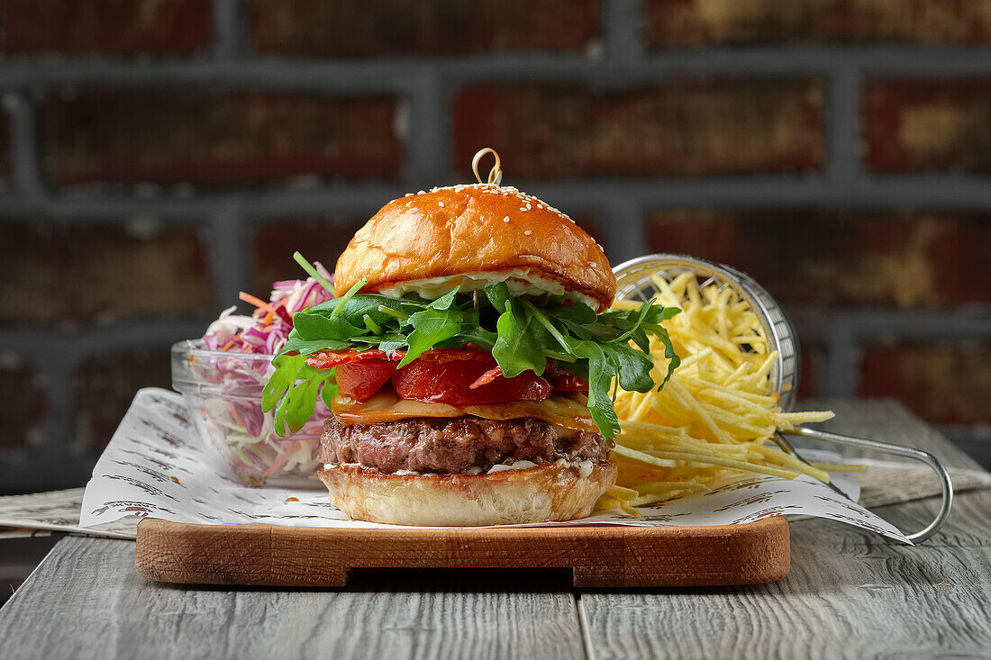 Bacon cheeseburger with tomatoes, rocket and chips, salad