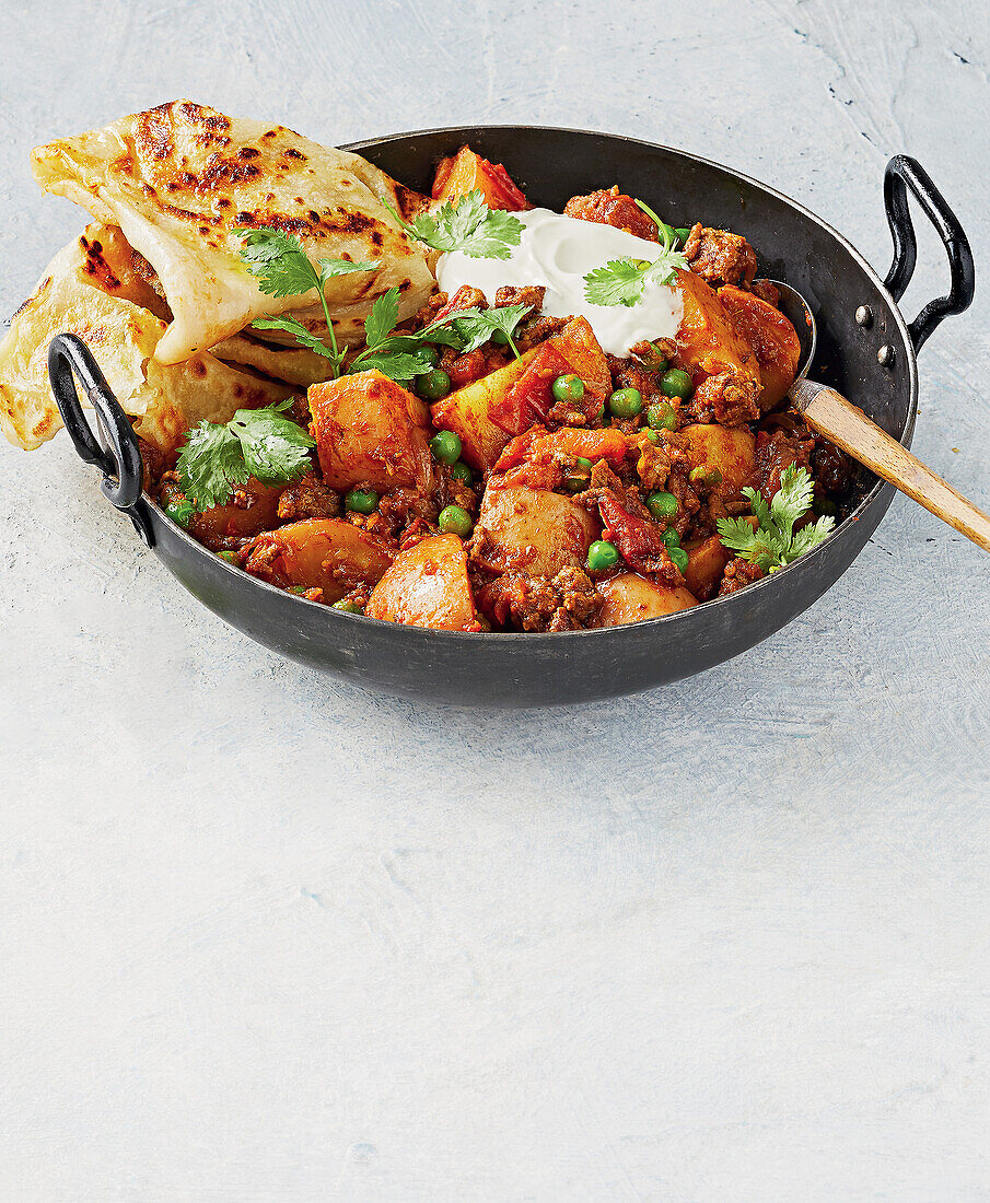 Potato and lamb curry with naan and peas