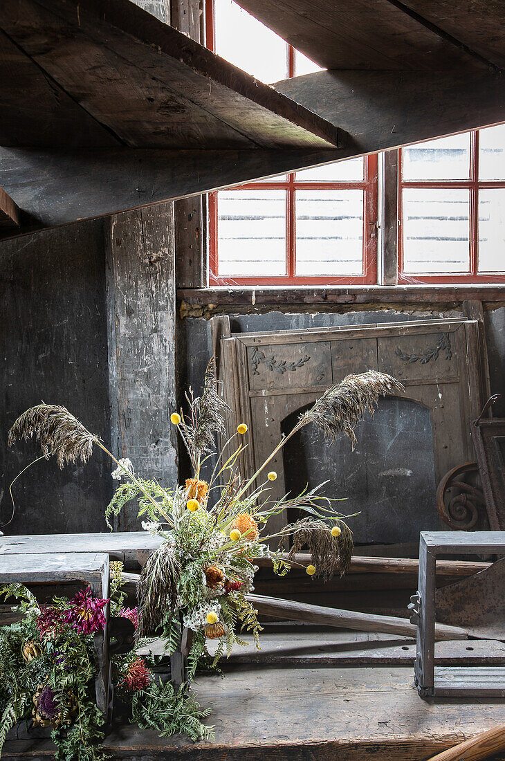 Dried flower arrangement in a rustic setting with red wooden lattice windows