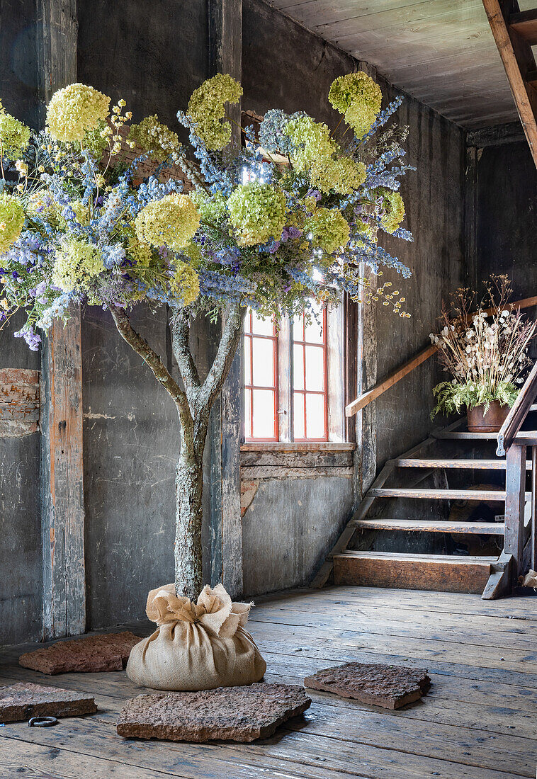 Tree with dried flower decoration, rustic wooden floor and stairs