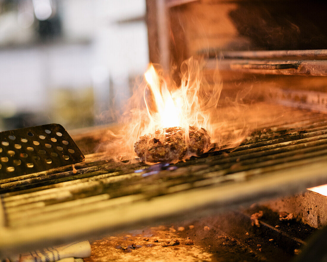 Burger Patty in Flammen auf dem Grill