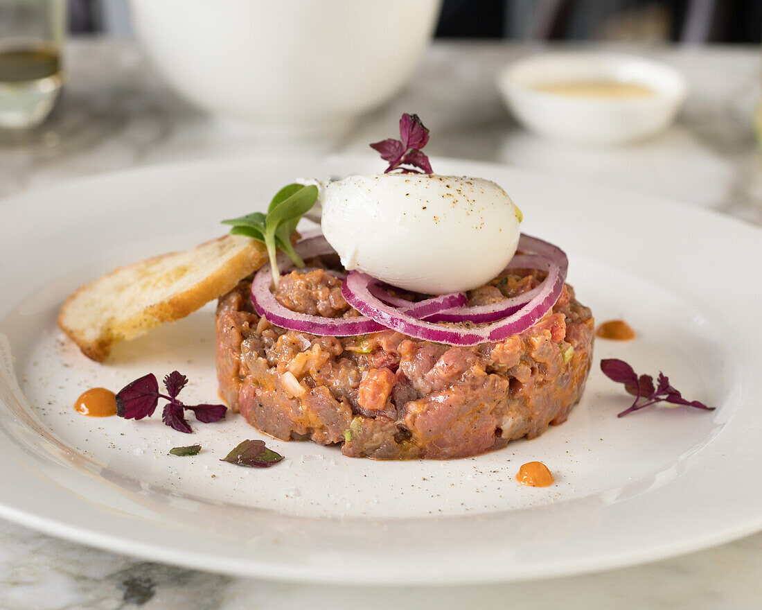 Steak tartare with onion rings and poached egg