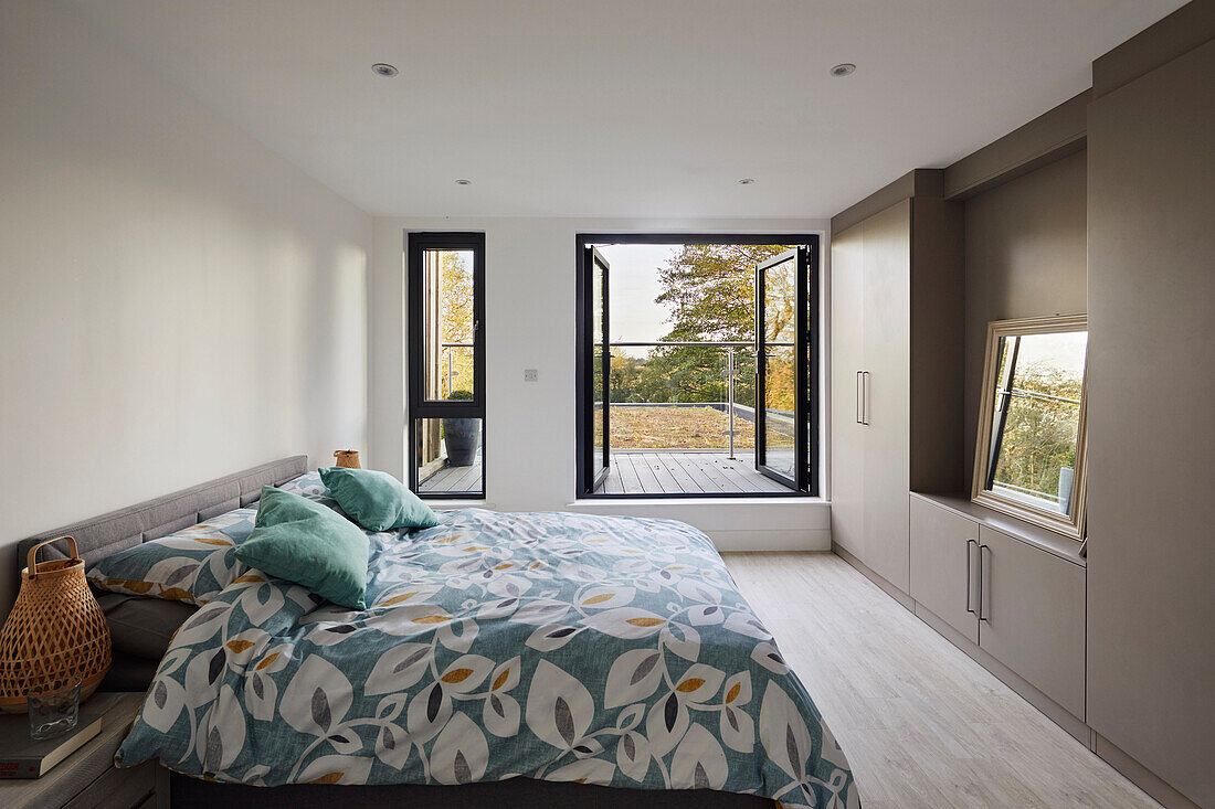 Double bed with patterned bed linen in bedroom with balcony