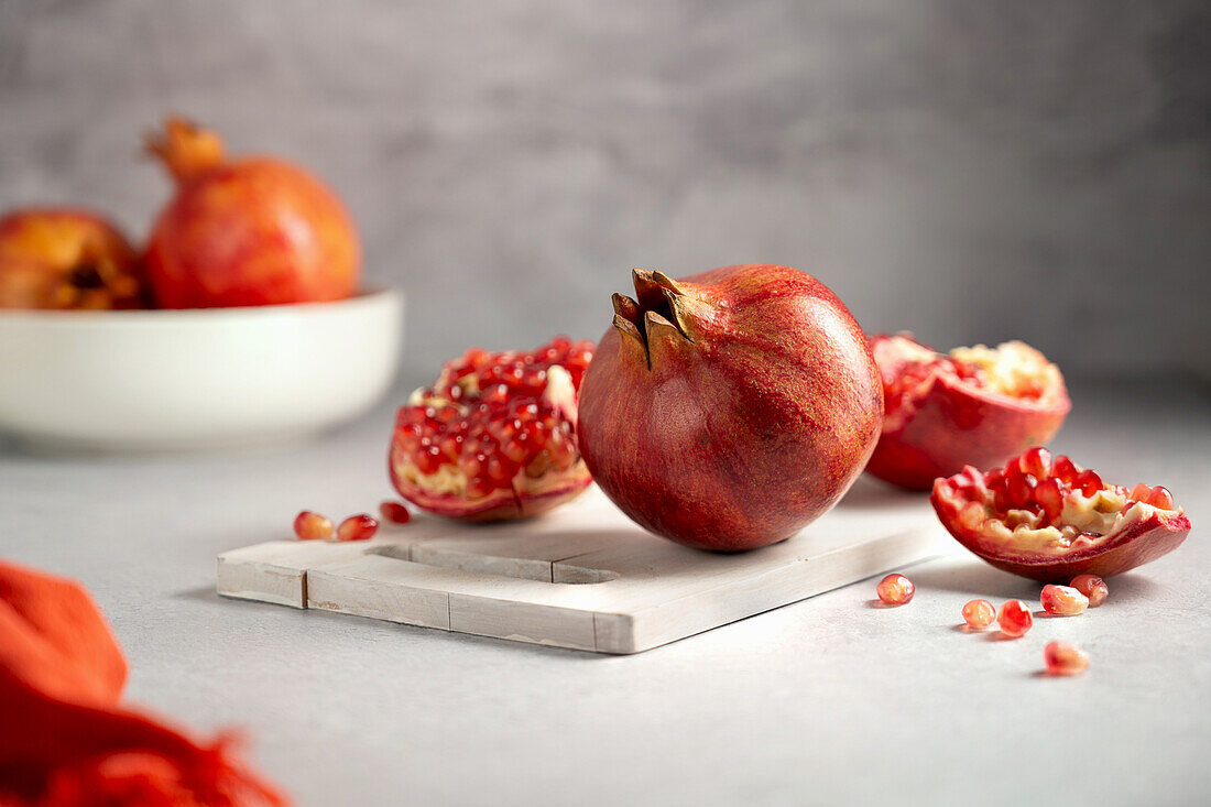 Pomegranate, whole and broken open on chopping board