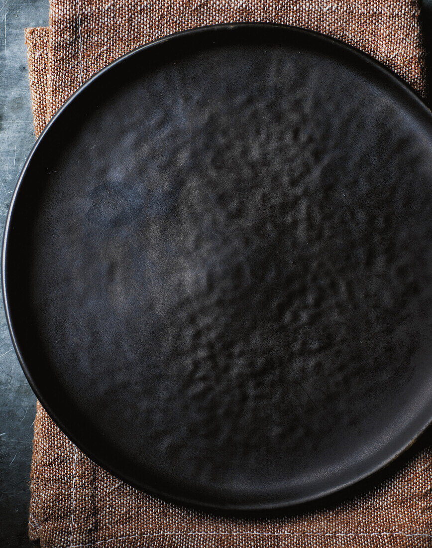 Dark ceramic plate on brown linen napkin