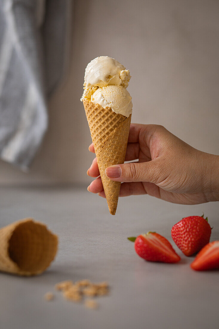 Homemade vanilla ice cream in a cone with strawberries