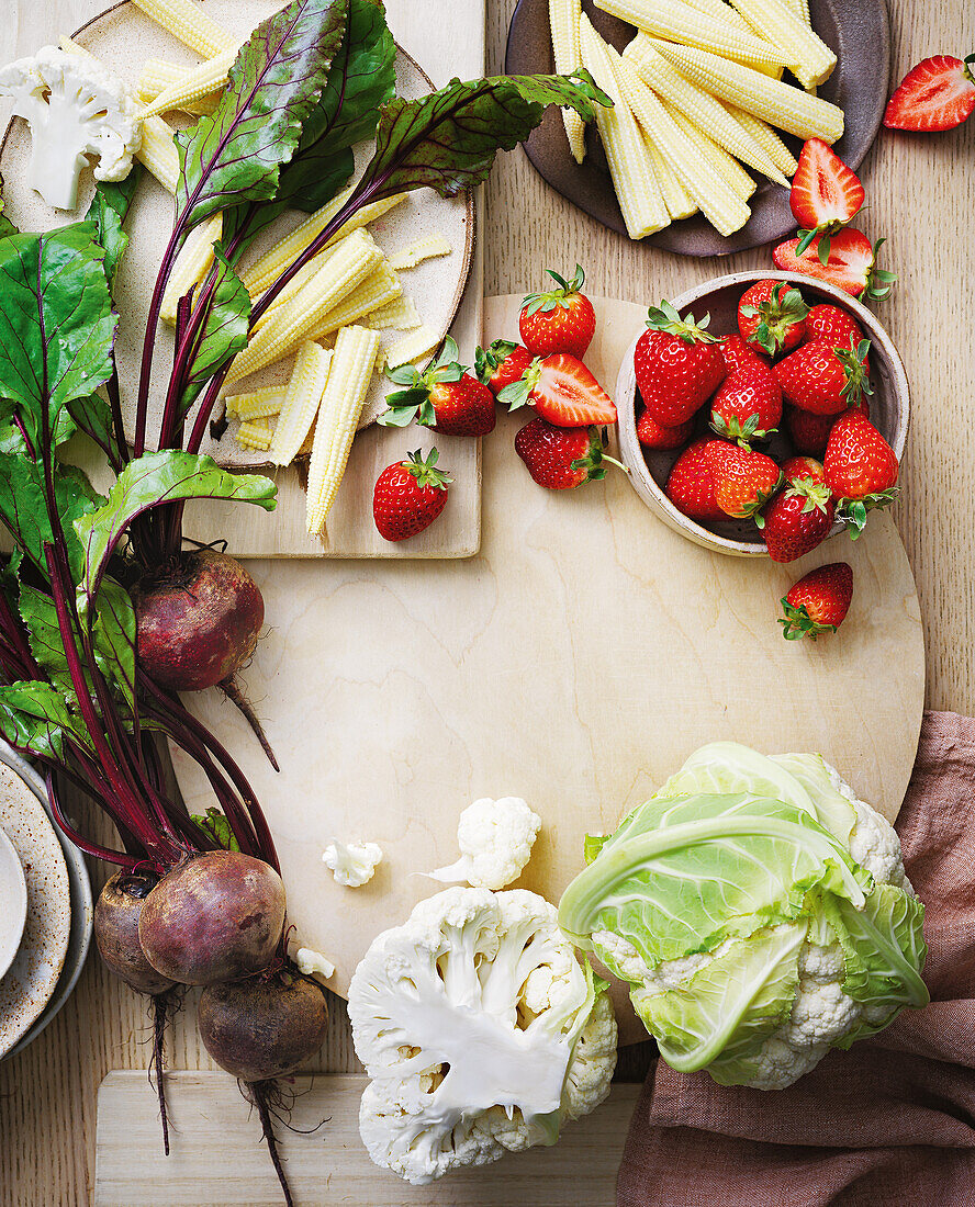 Frische Zutaten auf Holzbrett: Blumenkohl, Mais, Erdbeeren und Rote Bete