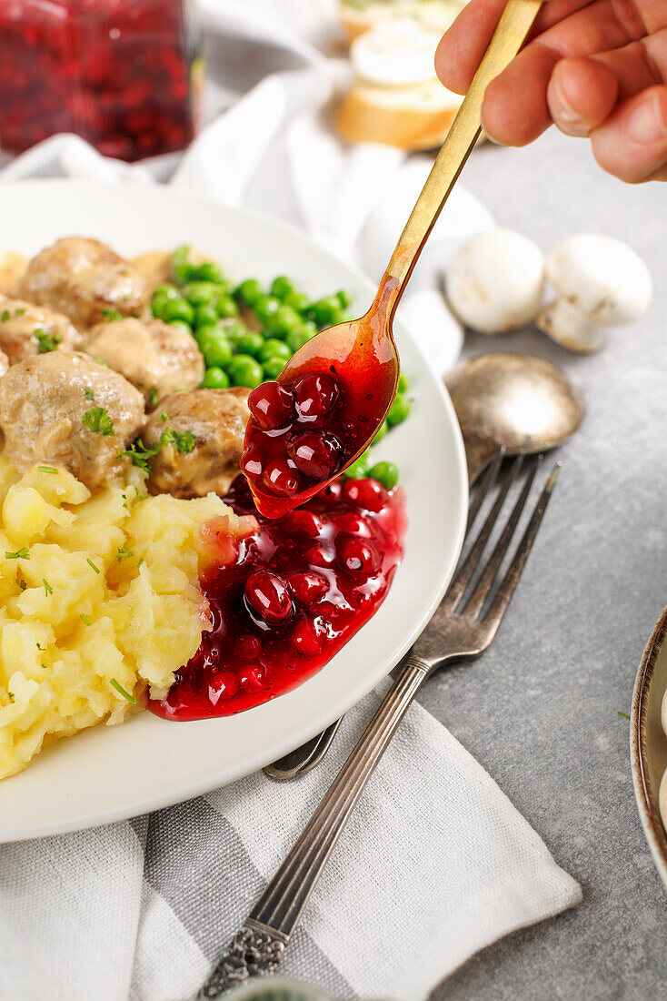 Köttbullar mit Kartoffelstampf, Erbsen und Preiselbeersauce