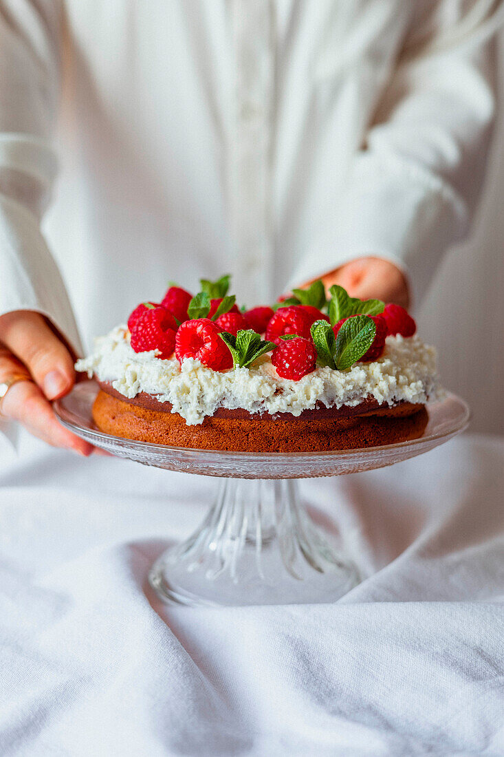 Chocolate cake garnished with fresh cream, raspberries and mint