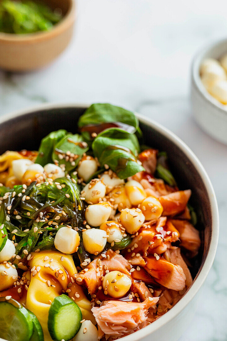 Poke Bowl mit Mozzarella, Gurken, Chuka, Tortellini und rotem Fisch