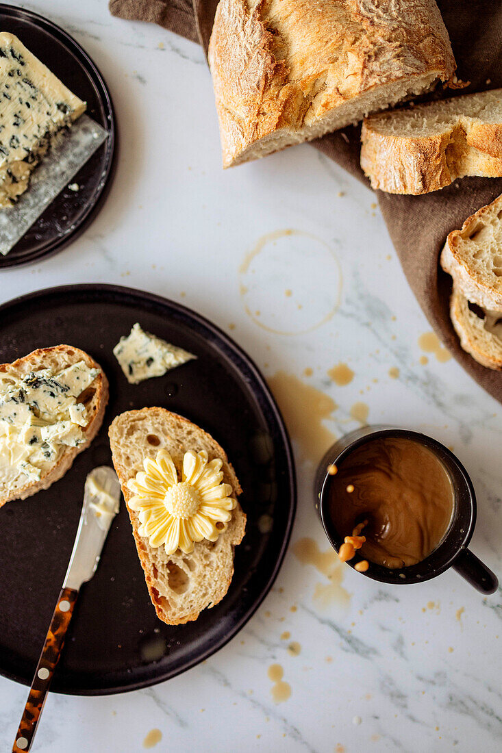 Aufgeschnittenes Weißbrot mit Butterblume, Blauschimmelkäse und Kaffee