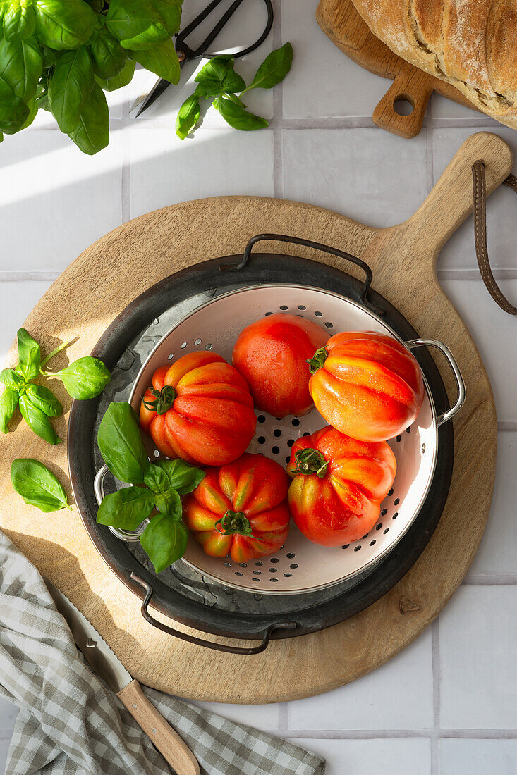 Ox heart tomatoes and fresh basil in a colander