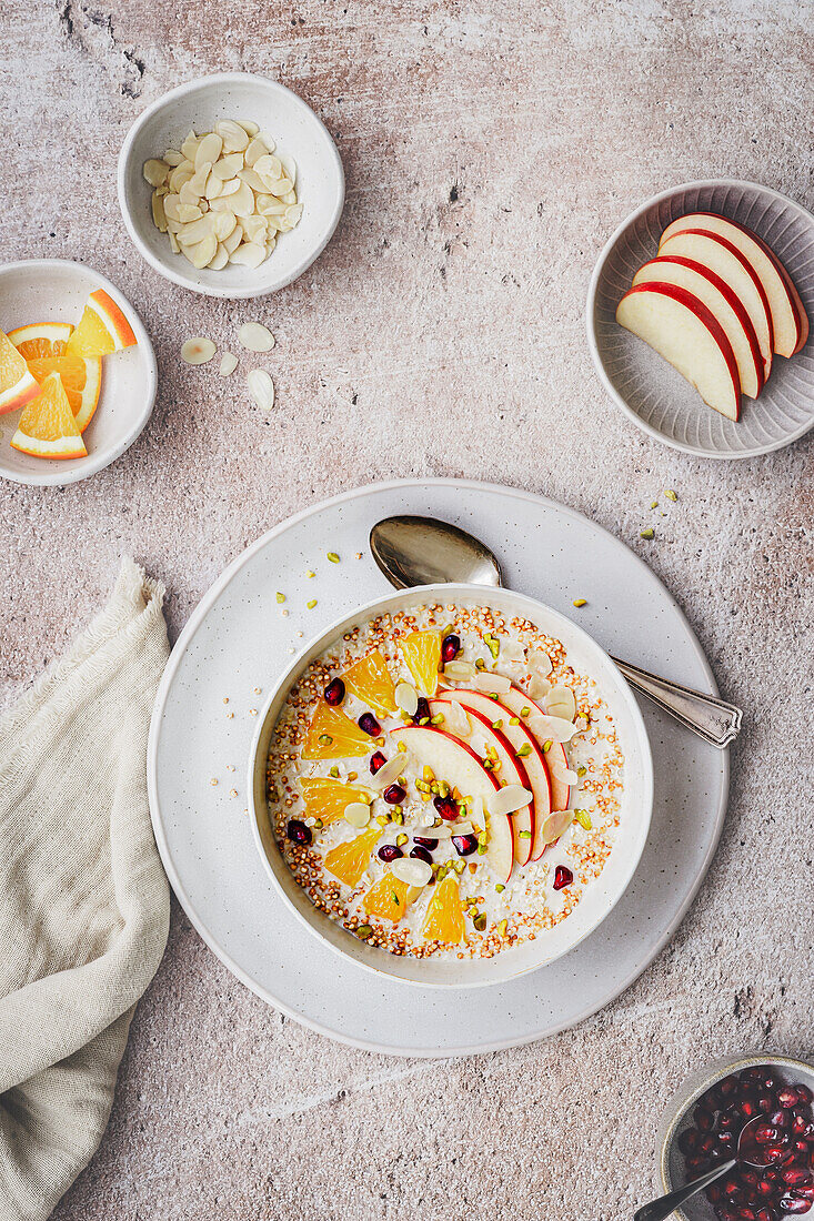 Porridge mit Apfelscheiben, Orange, Granatapfelkernen und Mandeln