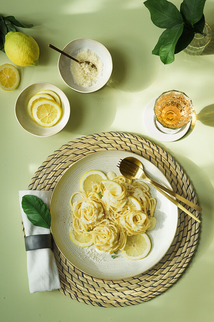 Spaghetti with lemon sauce garnished with lemon slices and parmesan cheese