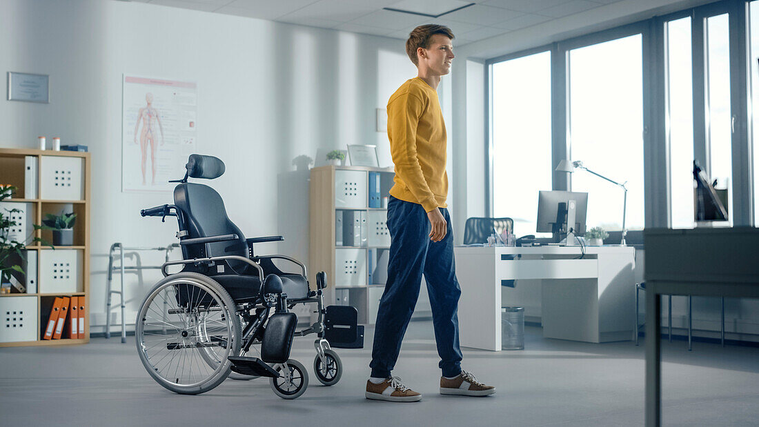 Male patient standing beside wheelchair in clinic