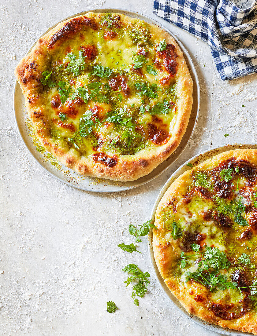 Pizza mit grünem Pesto und frischen Kräutern