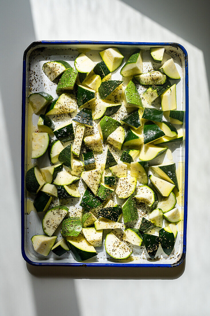 Roughly sliced courgette with olive oil and oregano before roasting