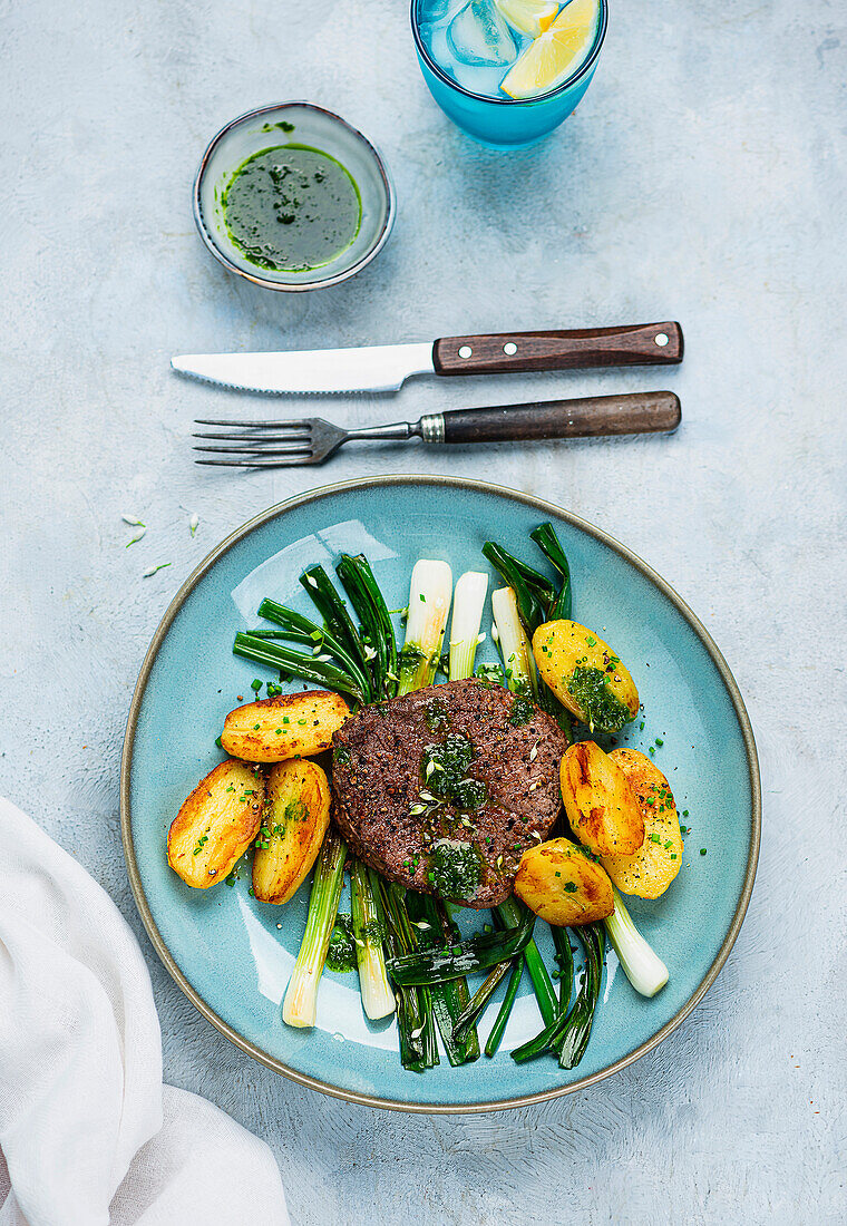 Beef steak with spring onions, roast potatoes and wild garlic oil