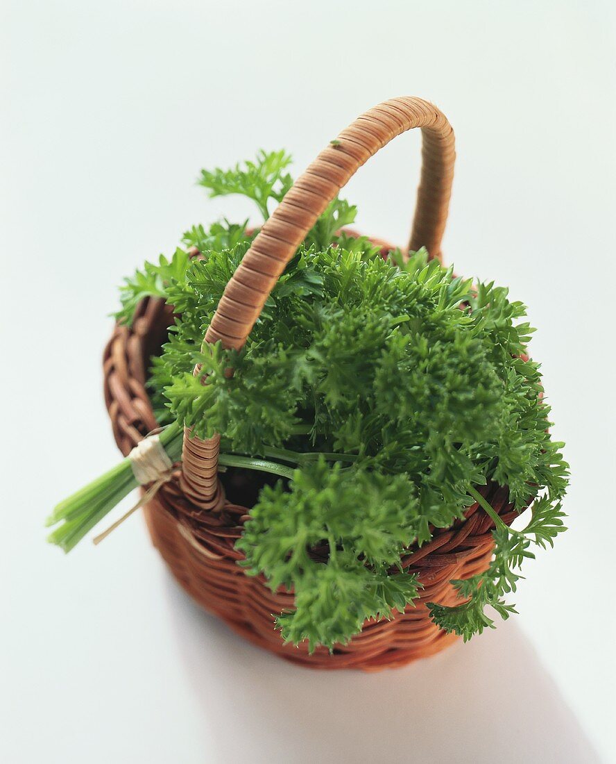 A bunch of curled parsley in small wicker basket