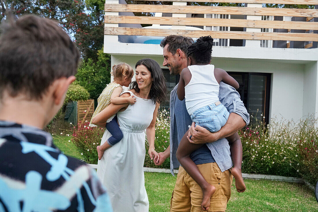 Parents with children playing in backyard