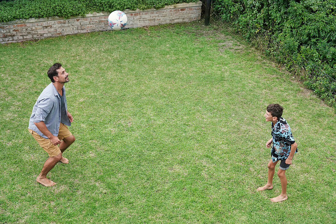 Father and son playing with ball in backyard