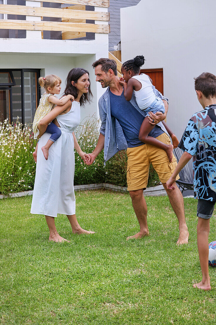 Parents with children playing in backyard