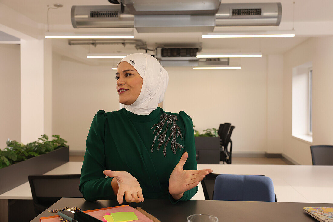 Smiling woman in headscarf talking in modern office