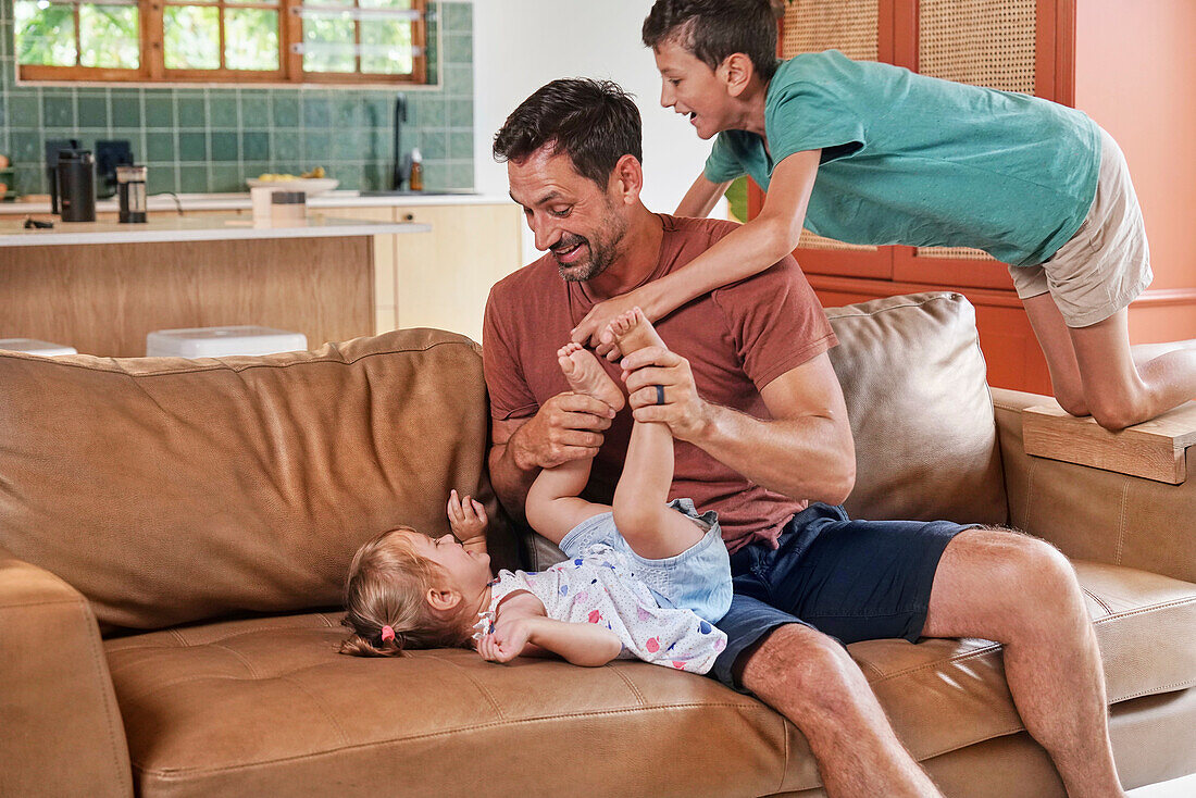 Father playing with children on sofa