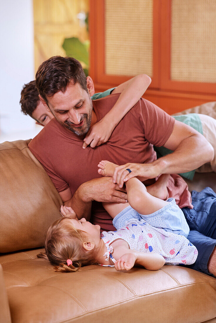 Father playing with children on sofa