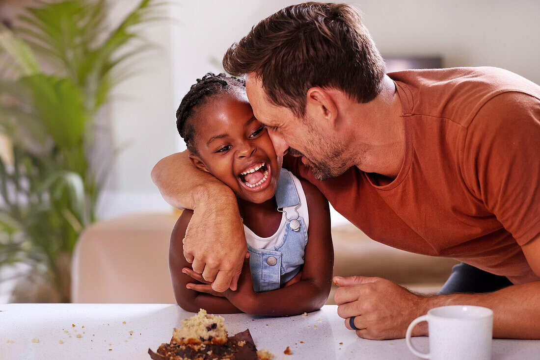 Father embracing smiling daughter at home