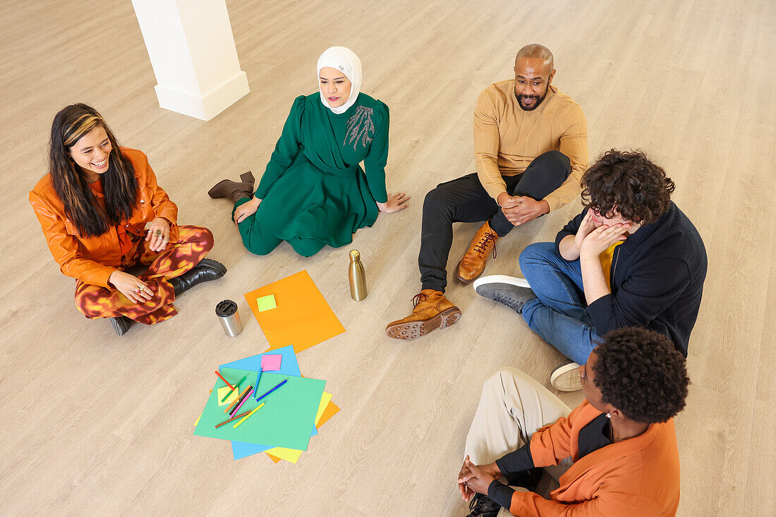 Company employees sitting on floor in office